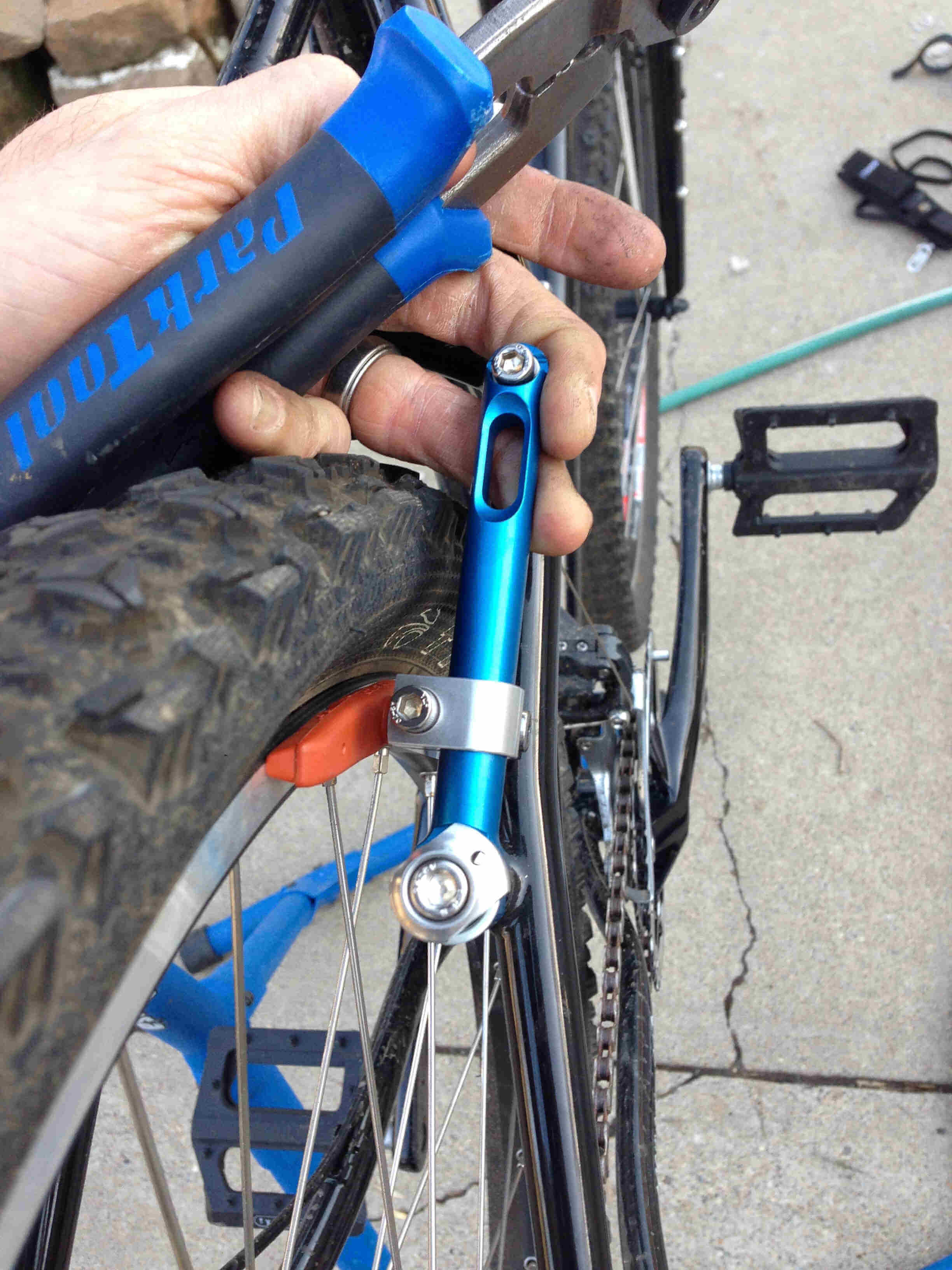 Rear, close up view of a person hand holding the rear, right side, brake caliper on a black Surly Troll bike