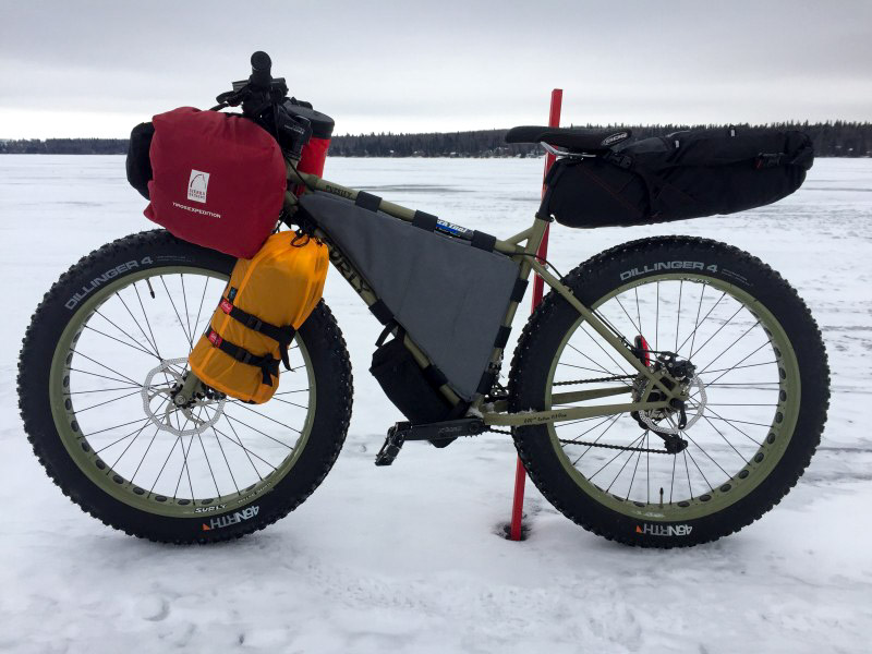Left profile of a Surly fat bike standing on a frozen lake, with trees in the background