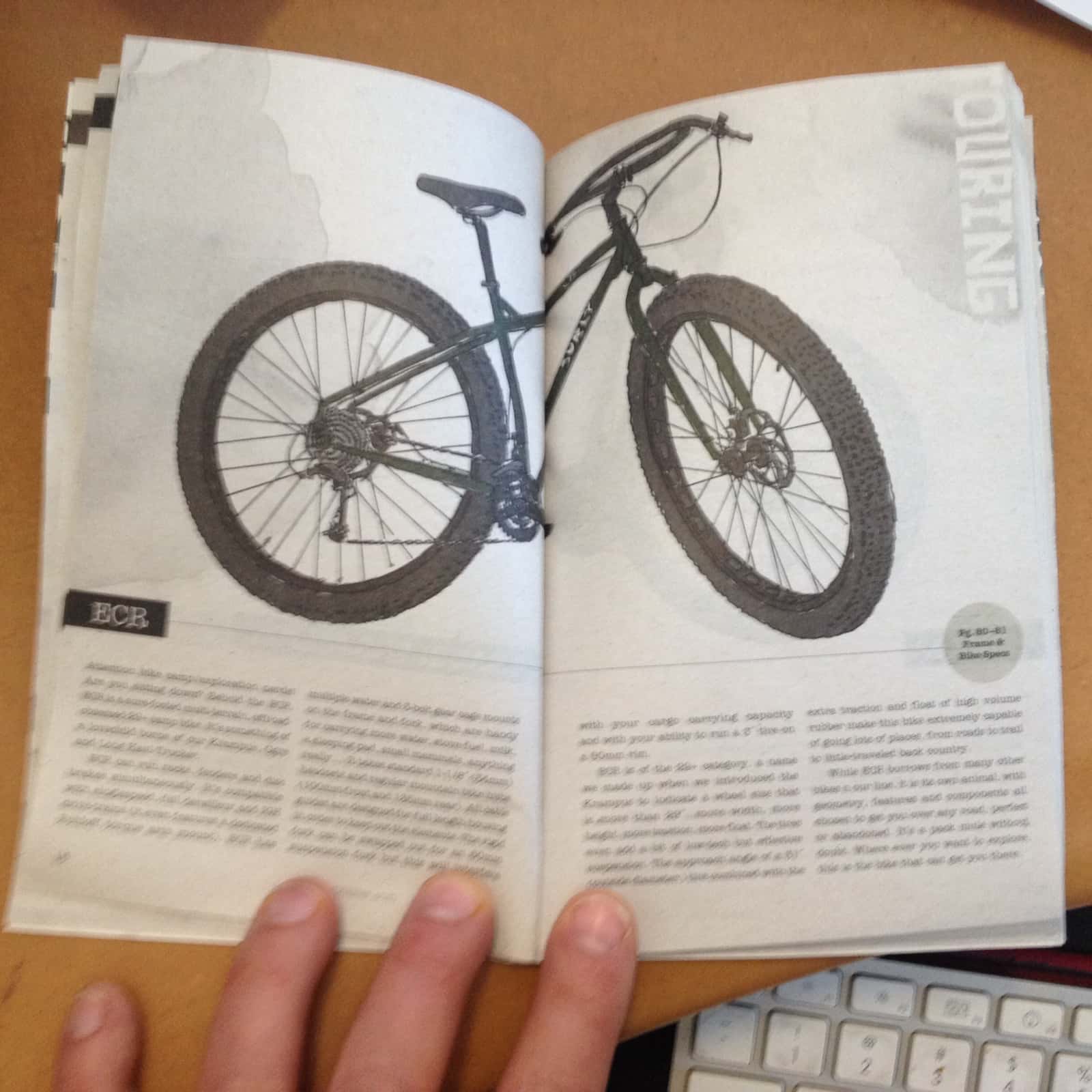 Downward view of an open catalog spread, showing a Surly ECR bike above and text below