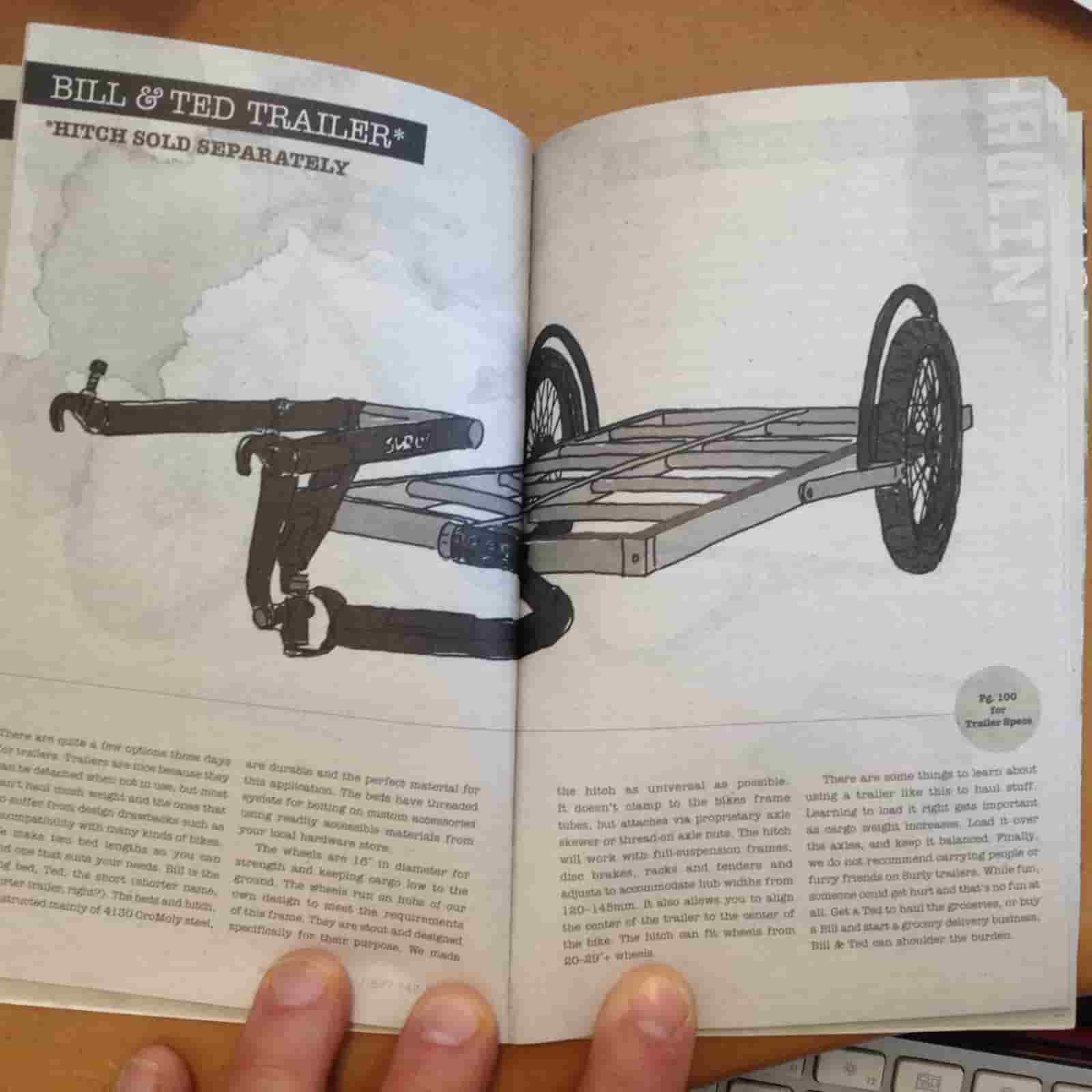 Downward view of an open catalog spread, showing a Surly Bill and Ted bike trailer above, and text below