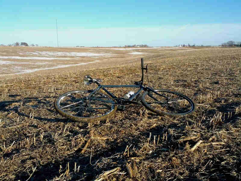 Right side view of a Surly bike, laying in a picked farm field, on it's left side