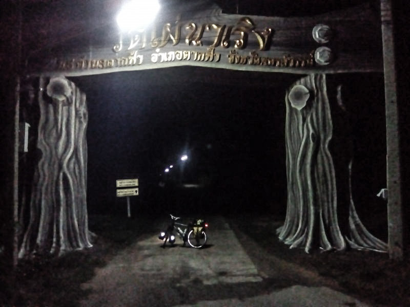 Left side view of a Surly bike, parked across a road, under an arched gateway at night