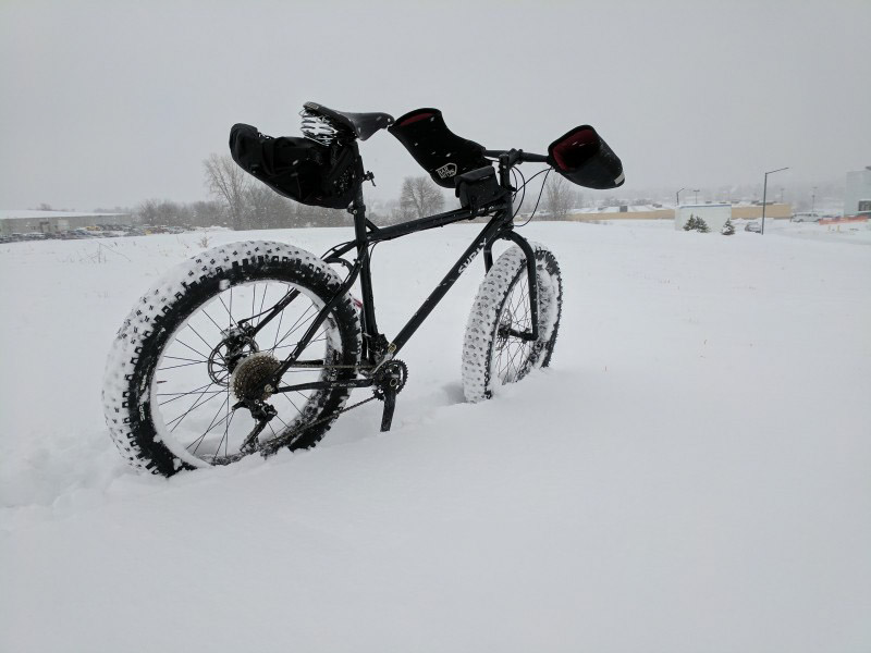 Rear right side view of a Surly fat bike standing in deep snow in a snowy field