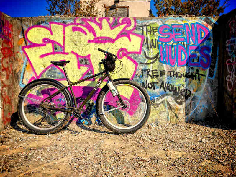 Right side view of a Surly bike leaning against a cement wall covered in graffiti
