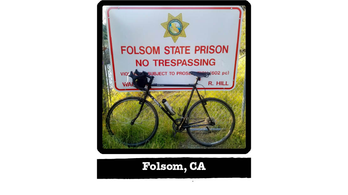 Left view of a black Surly bike in the grass, leaning on a Folsom State Prison sign - Folsom, CA tag below image