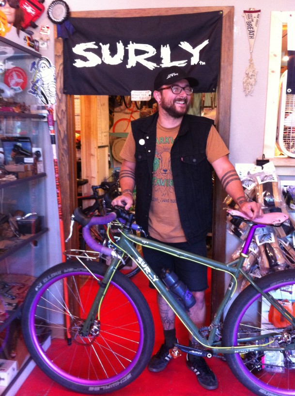 Left side view of a gray Surly Ogre bike with a person standing behind, in a bike shop