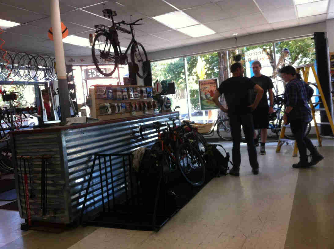 Three people standing next to the service counter in a bike shop