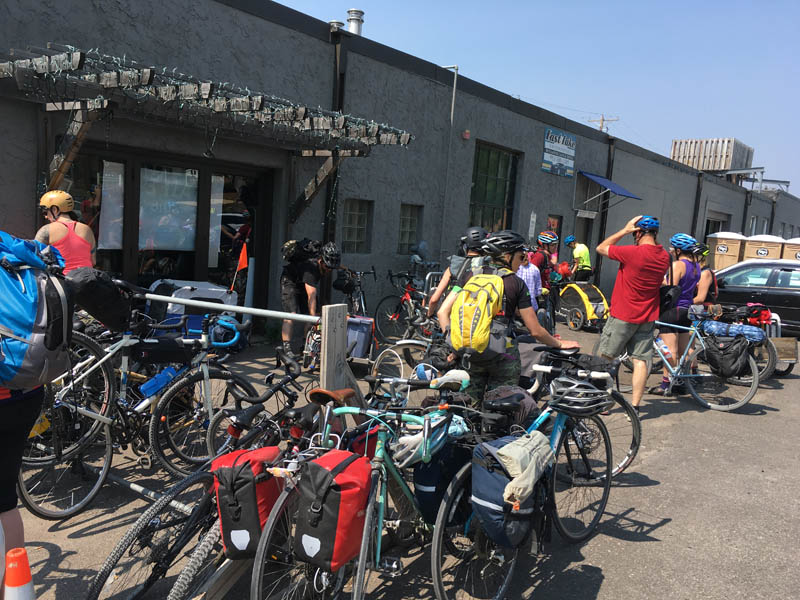 A gathering of people and parked bikes outside of a building