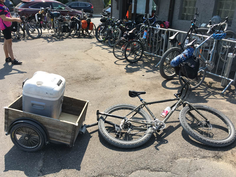 A bike laying on it's side with a trailer attached behind, with bikes parked in racks, all around