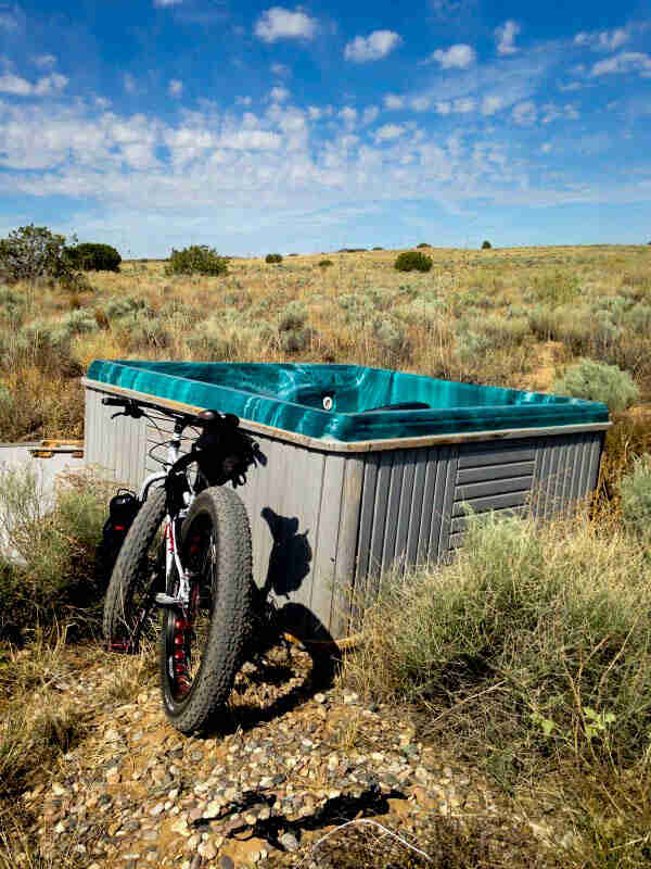 Rear view of a Surly fat bike, parked in front of a hot tub in a remote brushy, desert filed
