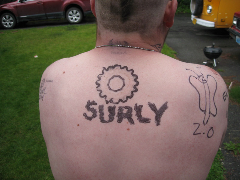 Rear view of a person's back, with a bike gear and SURLY drawn on it, in black marker