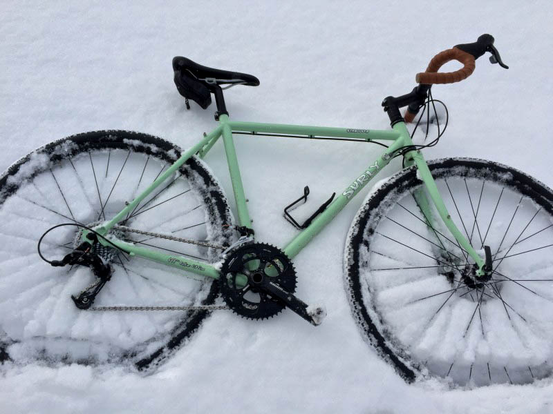 Downward view of the right side of a mint Surly bike laying in the snow