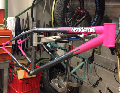 A Surly Instigator bike frame - pink and gray -  right side view - in a warehouse shop