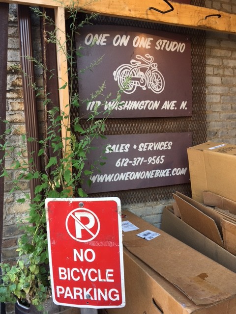 One on One Studio sign on a brick wall with a stack of cardboard boxes below