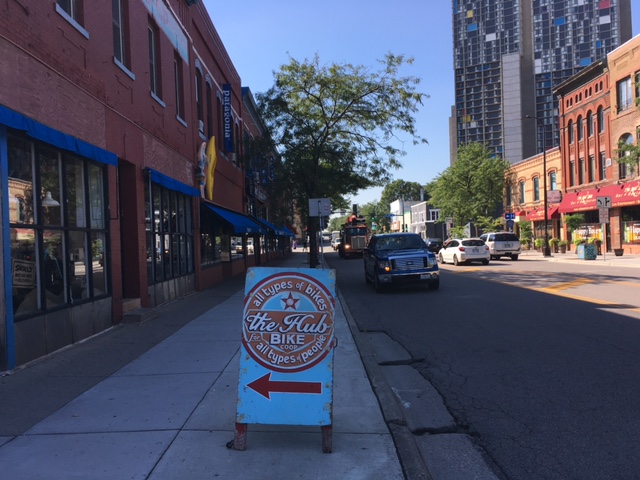 The Hub, bike shop sign set in the middle of a sidewalk next to a building