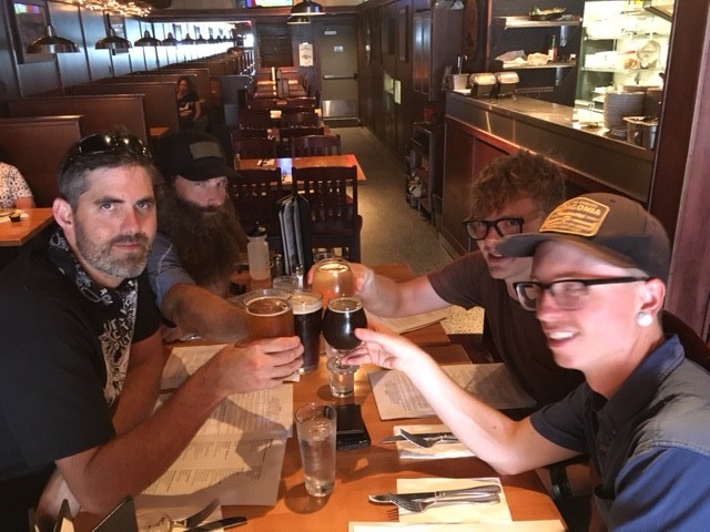 4 people sitting at a table in a diner, cheersing their glasses