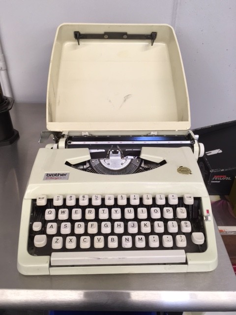 A white, Brother typewriter, sitting on top of a steel top table