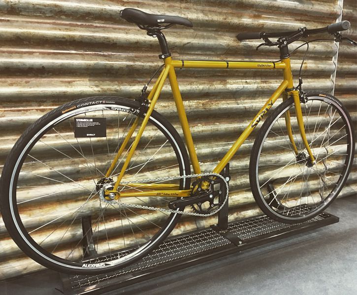 Right side view of Surly Steamroller bike, yellow, parked along a steel wall