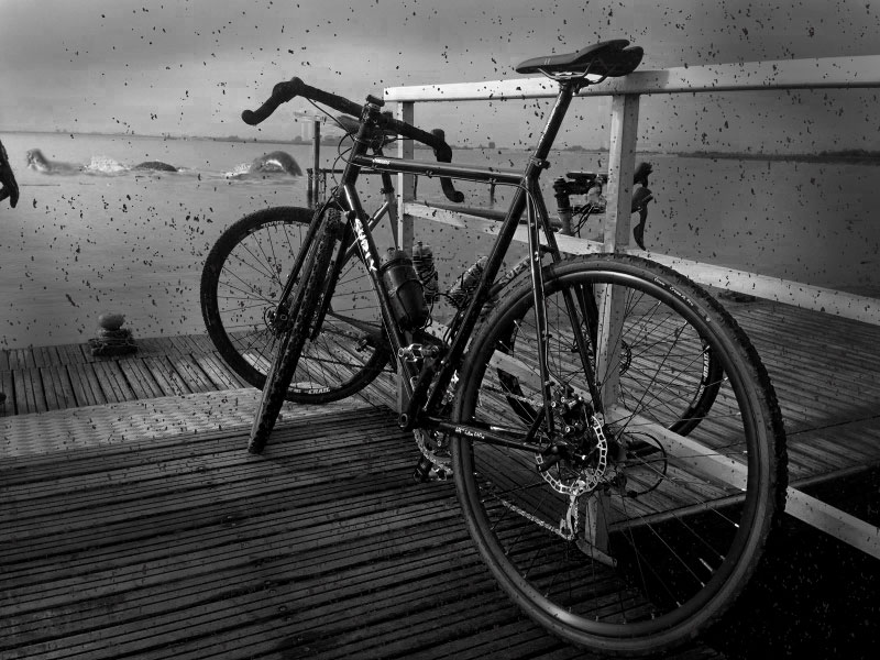 Left rear view of a Surly bike, on a dock, with a sea monster in the water ahead - black & white image