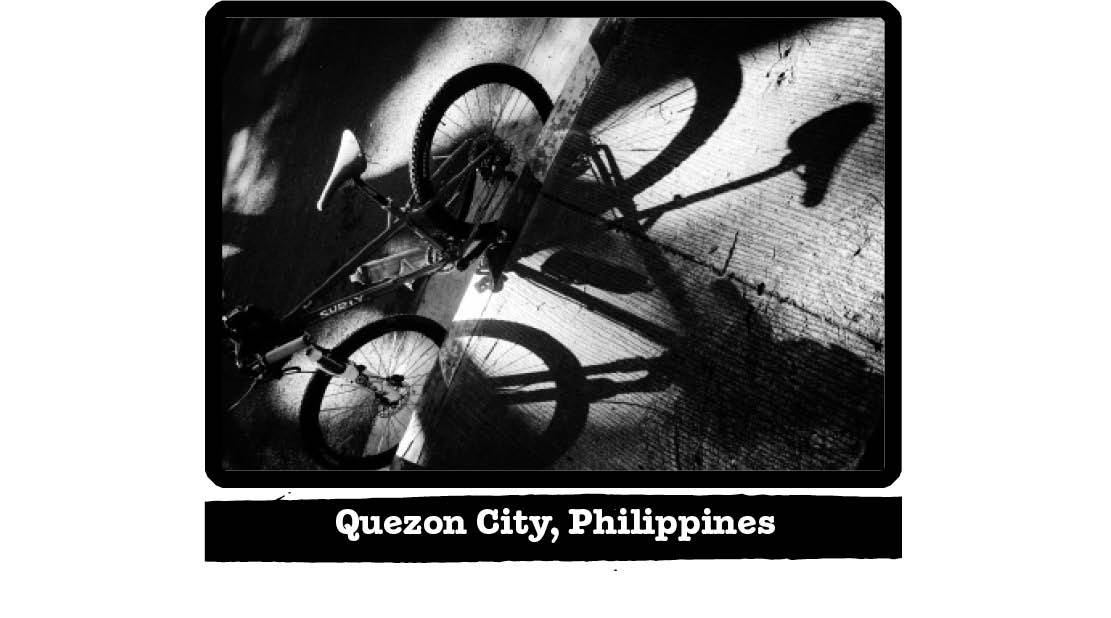 Tilted view, black and white photo of a Surly bike against a street curb - Quezon City, Philippines tab below image