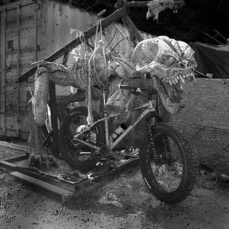 Right side view of a Surly fat bike, in front of a shipping container, with a monster figure above - black & white image