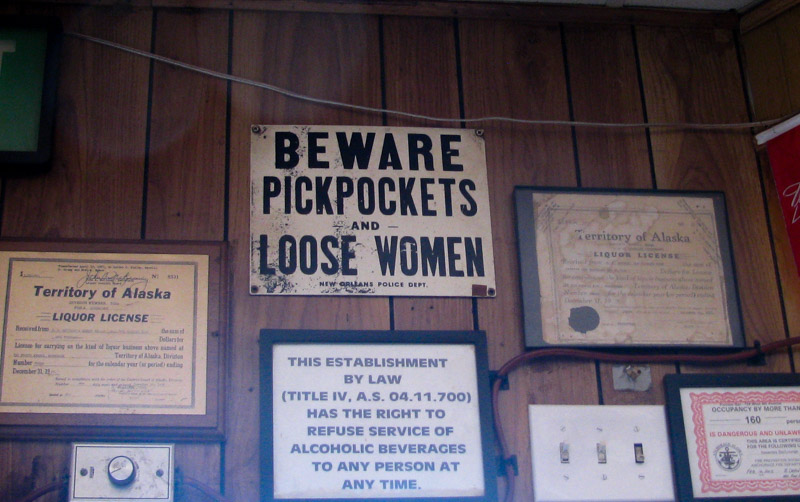 Front view of a wood paneled wall, with signs and certificates mounted to it
