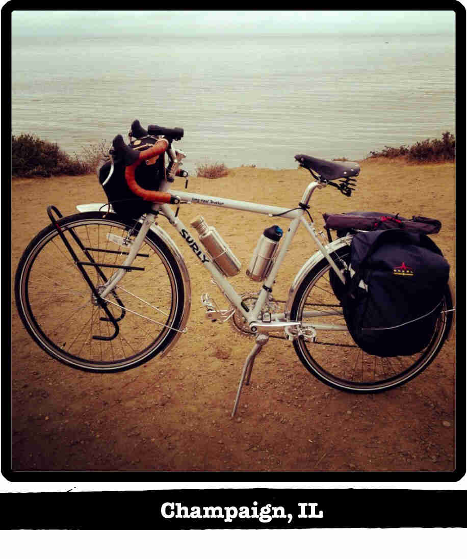 Left side view of a white Surly Long Haul Trucker bike, on gravel, next to a lake - Champaign, IL banner below image