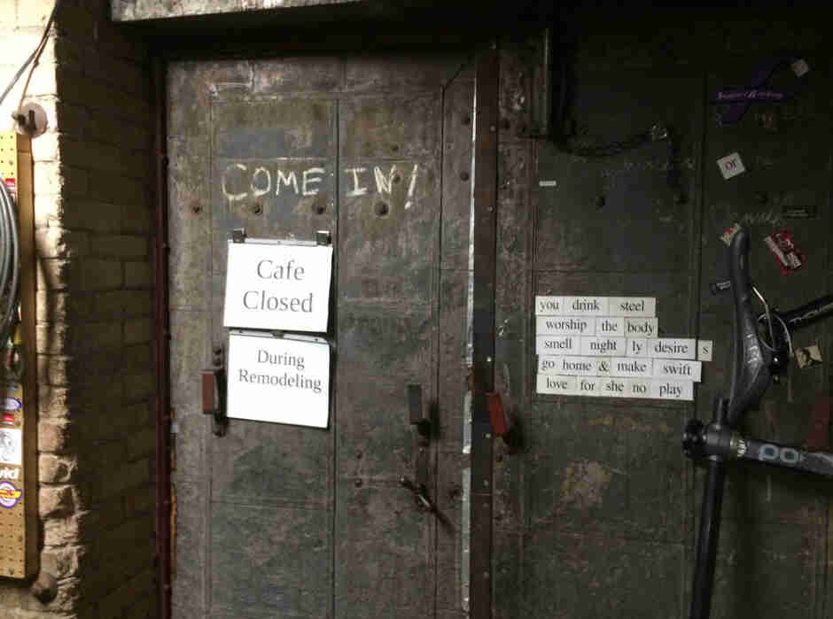 2 wood doors of a building with a sign reading, Cafe Closed During Remodeling, taped to one of the doors 