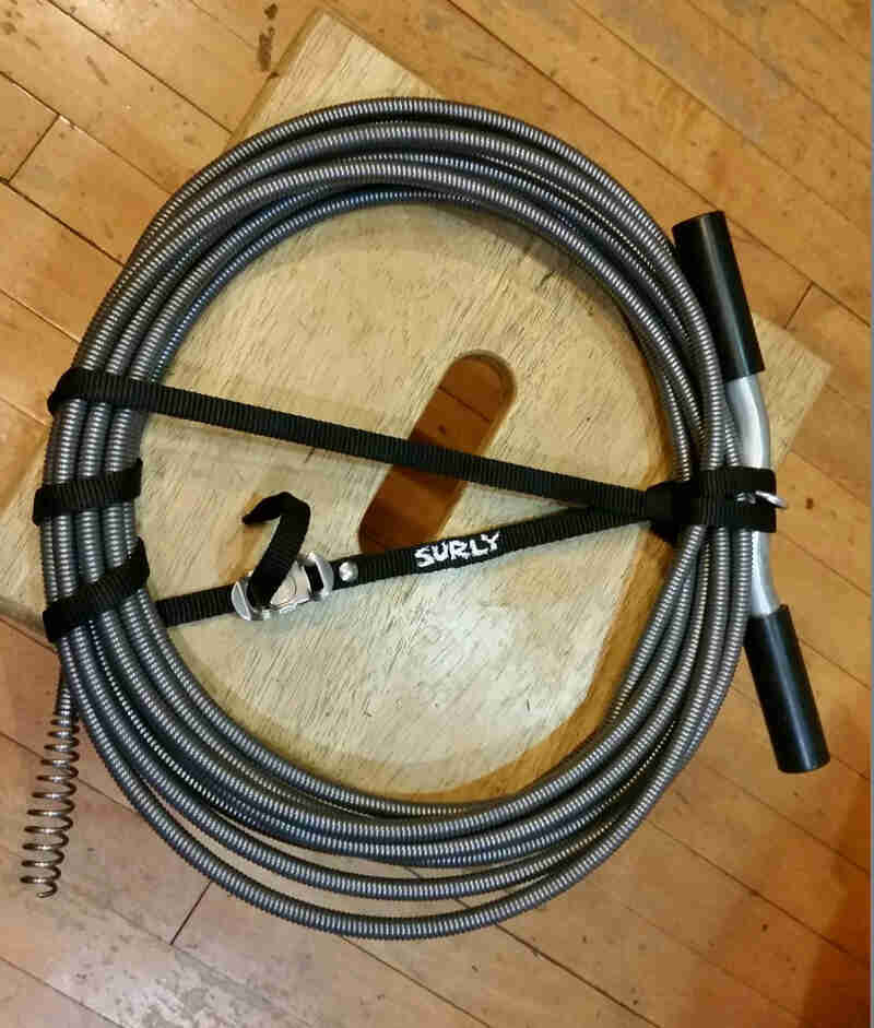 A Surly Junk strap - black - wrapped around a coil of a plumbing snake
