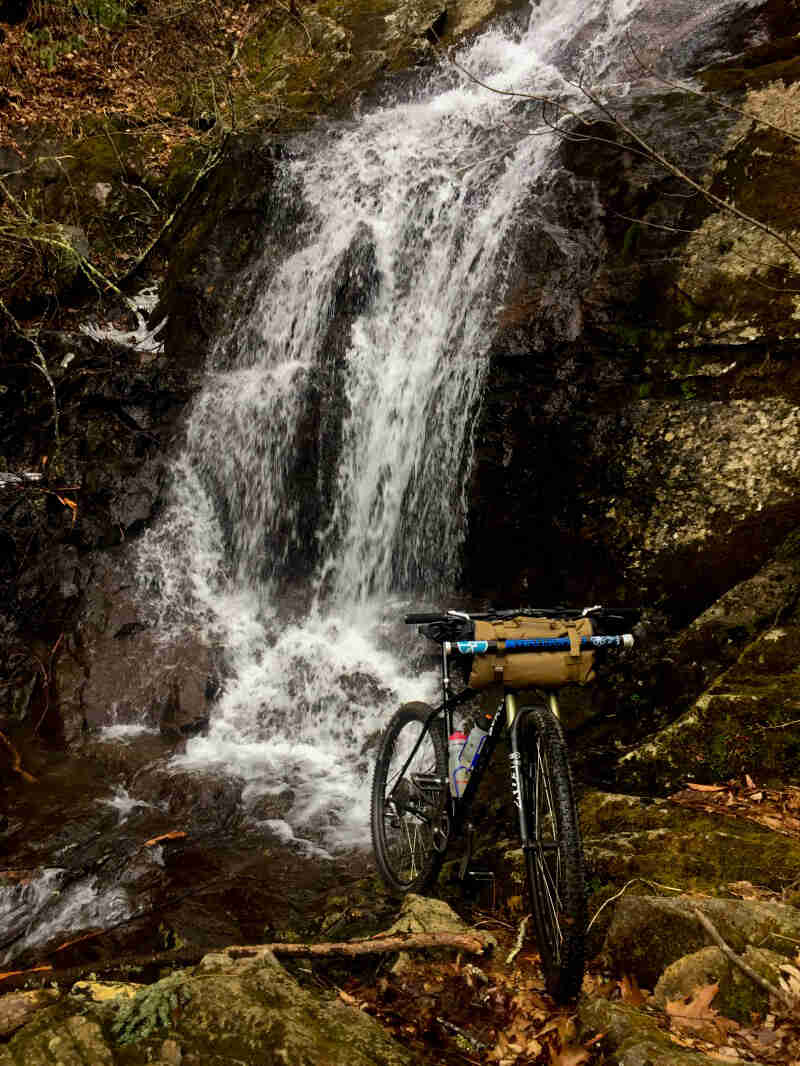 Front view of a Surly bike on rocks with a waterfall behind it
