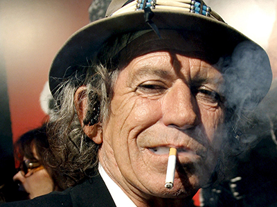 Headshot of Keith Richards wearing a hat and smoking a cigarette