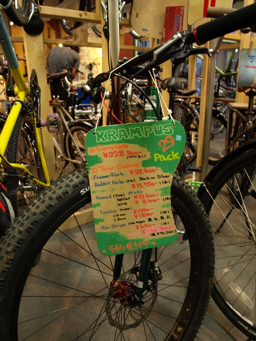 Front view of a green Surly Krampus bike with a sales tag hanging from the handlebar, inside of a bike shop