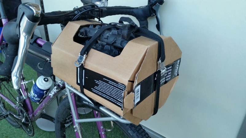 A Surly Junk strap - black - wrapped around a package of tire on a front rack of a bike