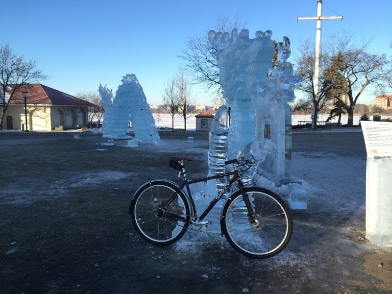 Right side view of a black Surly Karate Monkey bike, parked against an ice sculpture in a field, with more behind
