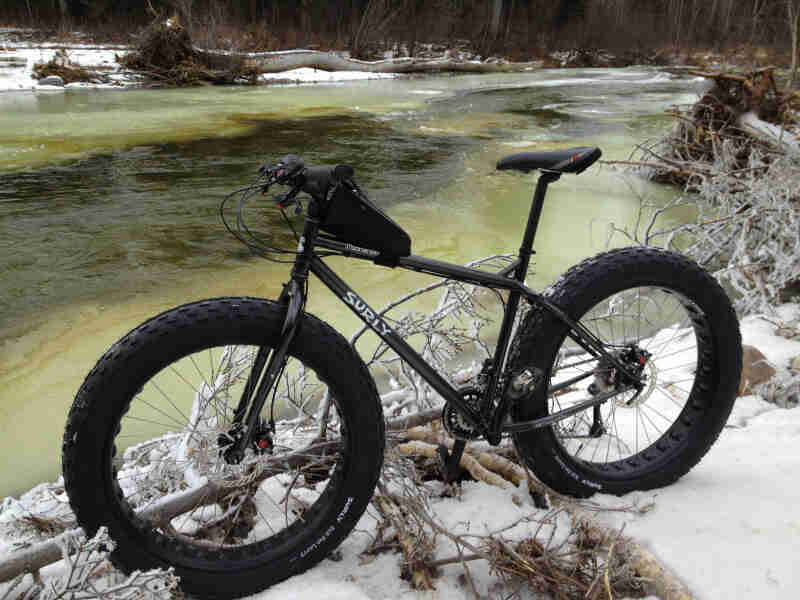 Left side view of a Surly Moonlander fat bike on a snowy river bank