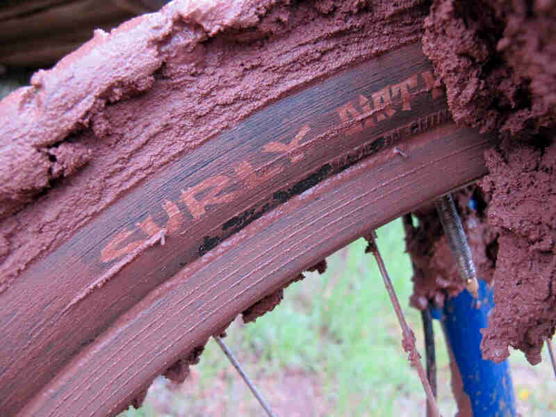 Cropped partial view of a Surly tire and rim covered in red clay mud