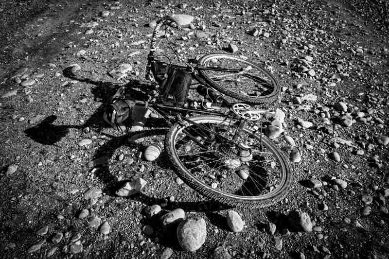 Rear view of a Surly Cross Check bike, laying on it's left side on gravel - black & white image