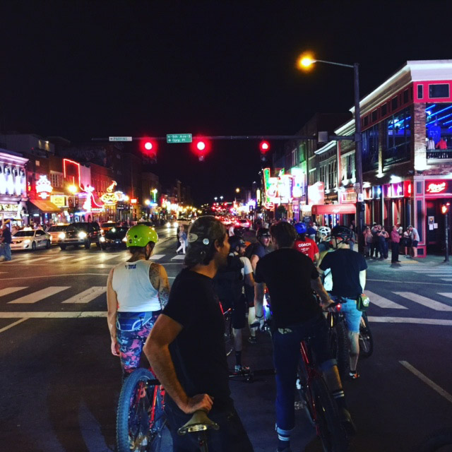 Rear view of a group of cyclists, at a stop light on a city street at night
