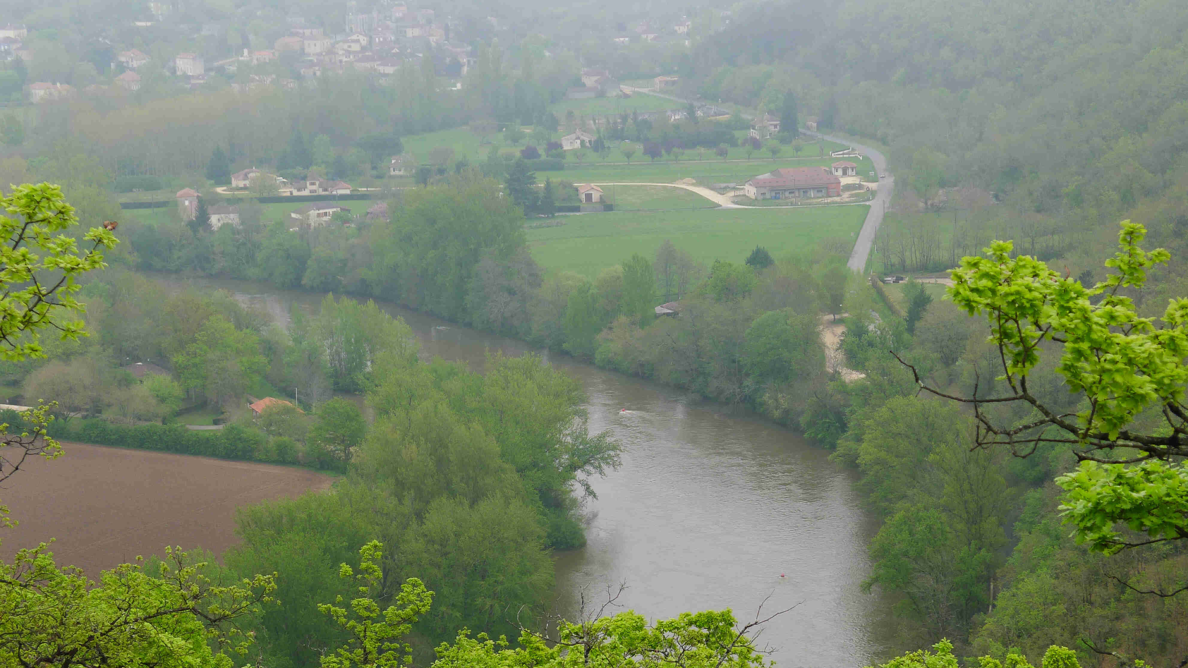 High, downward view of a green river valley, with a town in the background