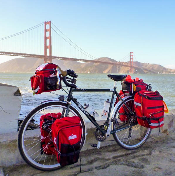 Right profile of a bike, loaded with gear, parked on a roadside, with the Golden Gate bridge and bay in the background