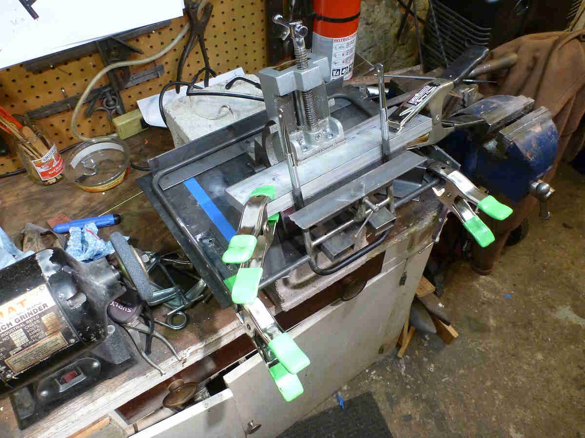 Downward view of a Surly 24-Pack rack prototype, clamped in a vise on a workbench in a shop