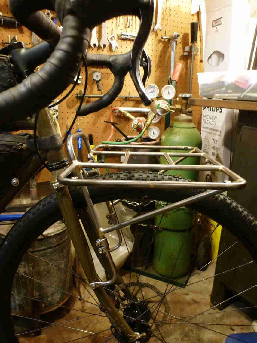 Right side view of a Surly 24-Pack rack prototype mounted to a bike fork, in front of a gas welding system, in a shop