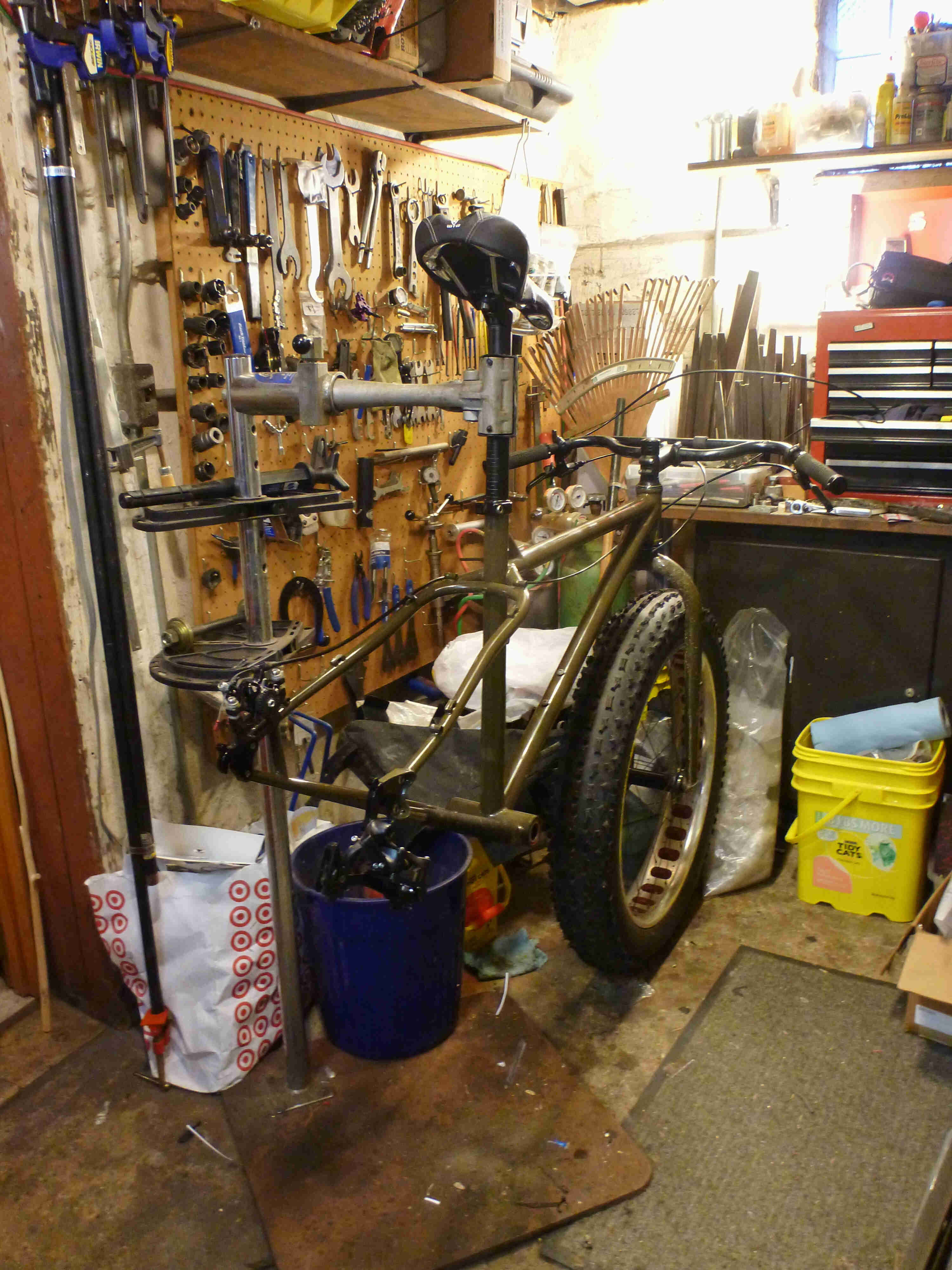 Rear view of a Surly Ice Cream Trucker fat bike, minus the drive train or rear wheel, on a stand in a workshop