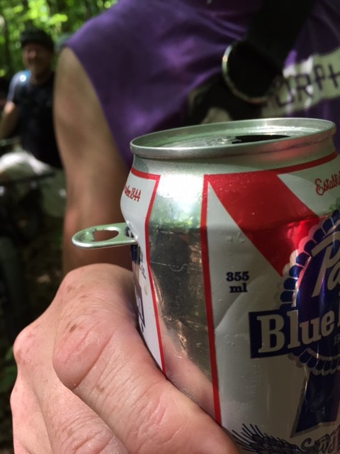 Close up of a person's hand holding up a Pabst Blue Ribbon beer can