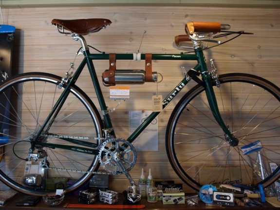 Right side view of a green Surly Pacer bike, on a table display against a wall, inside of a bike shop