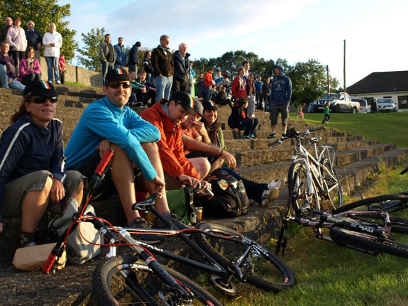 Front, right side view of people sitting and standing on a long set of stone steps, with their bikes in front of them