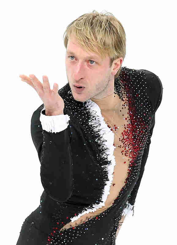 Front, waist up view of a figure skater, with a white background behind them