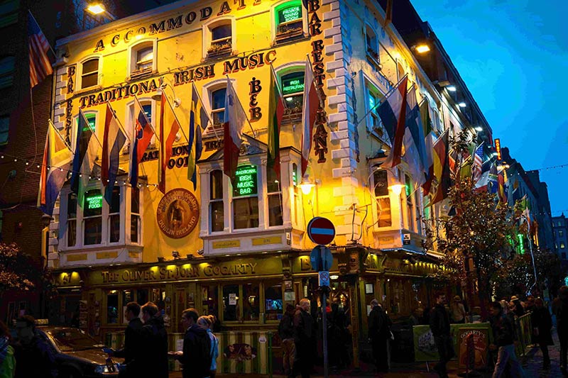 Outside, nighttime view of a bar restaurant with country flags hanging from it, in Dublin, Northern Ireland