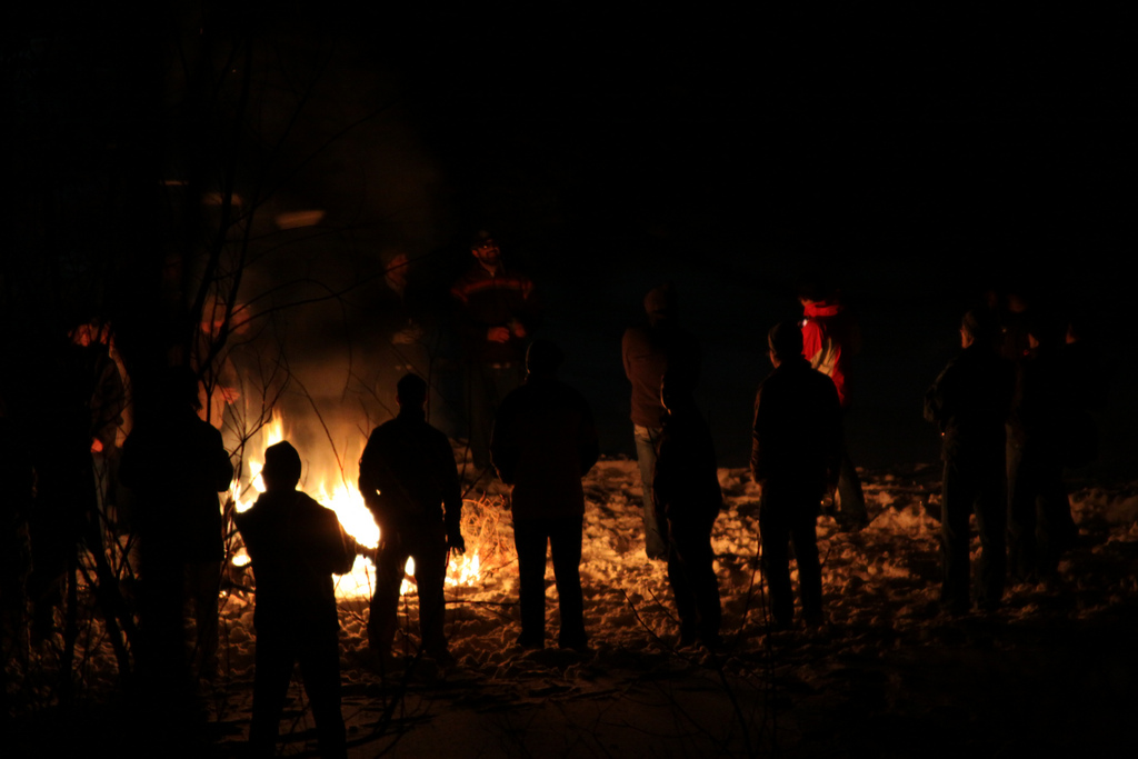 People standing around a campfire at night