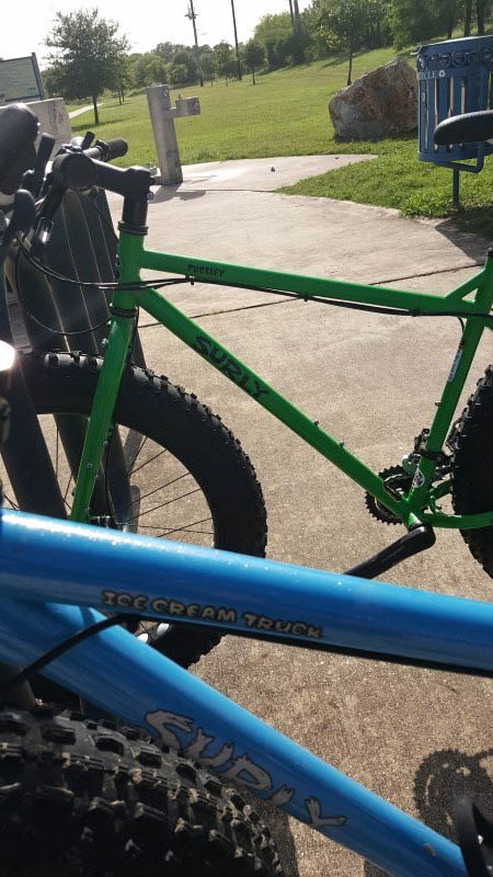 Cropped left side view of Surly, Ice Cream Truck and a Pugsley fat bikes, parked in bike rack at a park